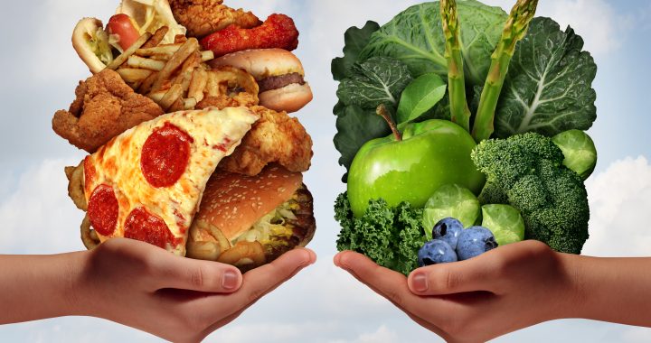 Nutrition choice and diet decision concept and eating choices dilemma between healthy good fresh fruit and vegetables or greasy cholesterol rich fast food with two hands holding food trying to decide what to eat.